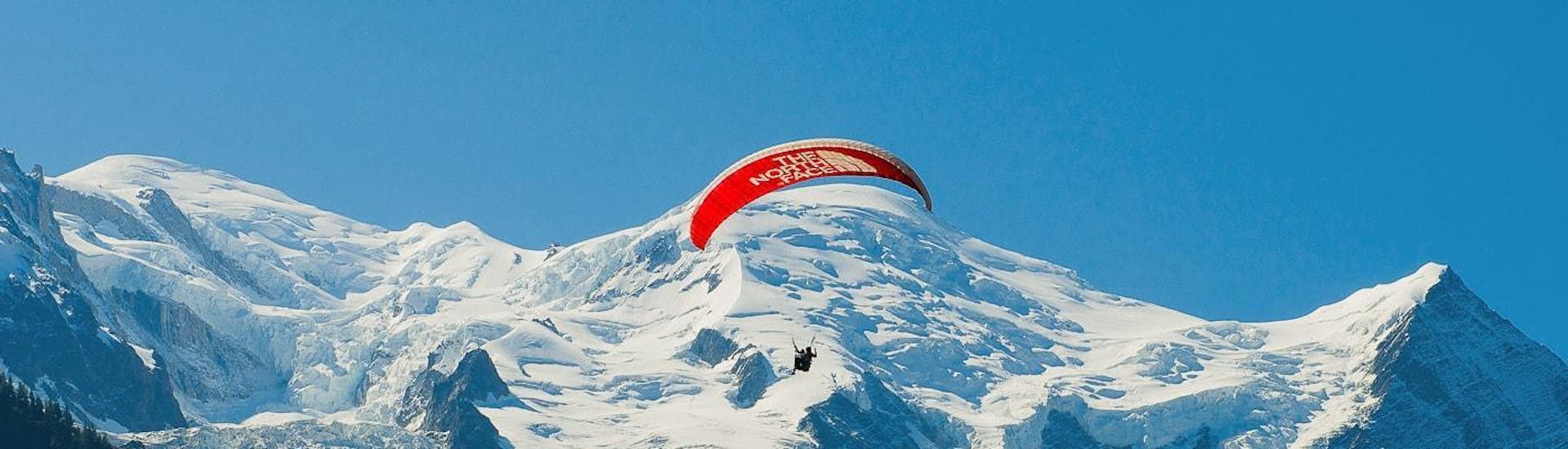 Ein Paragliding-Pilot von Kailash Paragliding führt im Sommer einen Tandem-Flug von Planpraz - Chamonix über eine atemberaubende Bergkulisse durch.