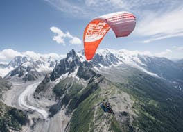 A paragliding pilot from Kailash Paragliding is doing a Tandem Paragliding Flight from Planpraz - Chamonix above stunning mountain scenery in summer.