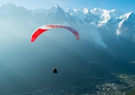 Ein Paragliding-Pilot von Kailash Paragliding führt einen Tandem-Flug mit dem Gleitschirm vom Plan de l'Aiguille über dem Tal von Chamonix durch.