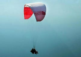 Een paraglidingpiloot van Kailash Paragliding doet een tandemparaglidingvlucht "Free style" tegen een bergdecor.