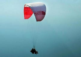 Een paraglidingpiloot van Kailash Paragliding doet een tandemparaglidingvlucht "Free style" tegen een bergdecor.
