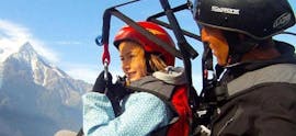 A child is enjoying their Tandem Paragliding Flight for Kids (4-12 years) with an experienced pilot from Kailash Paragliding.
