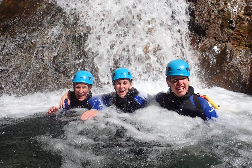 Eine Gruppe, die am Canyoning "Sensation" - Canyon de Montmin teilnimmt, lächelt unter dem Wasserfall.