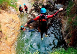 A person jumps into the water during the Classic Canyoning in the Lentegí River.