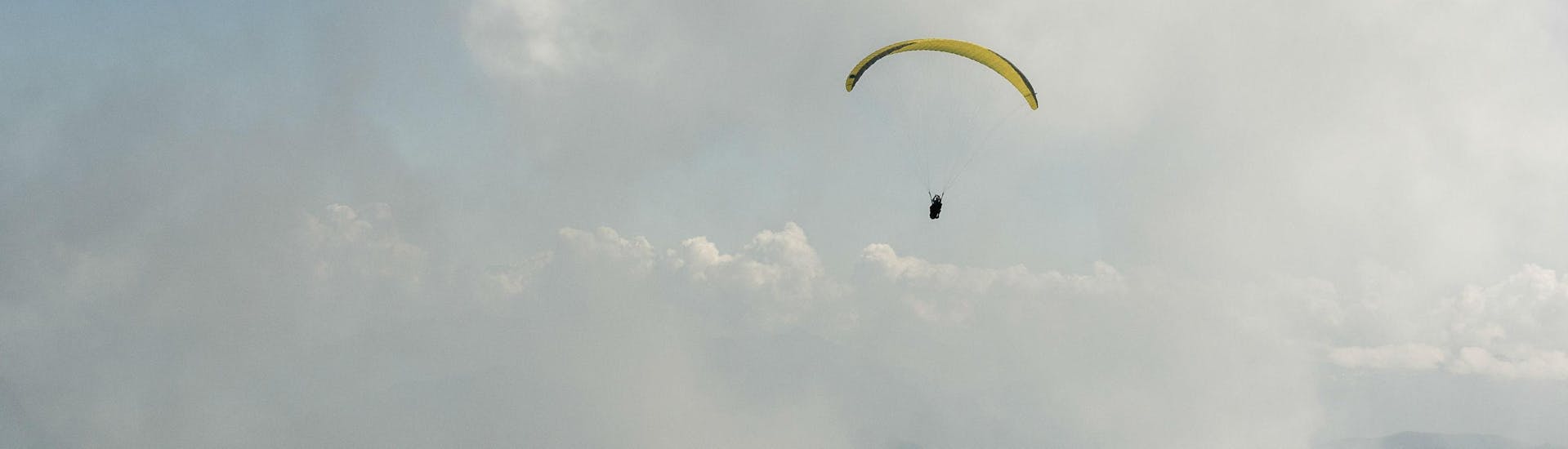 A paraglider is flying among the clouds during their Tandem Paragliding "Performance" - Chartreuse with Prévol Paragliding.