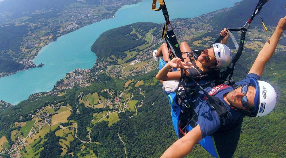 Een vrouw vliegt over Annecy tijdens haar tandemparagliding bij het meer van Annecy - acrobatische vlucht met Takamaka Annecy.