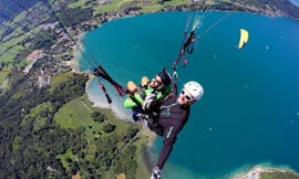 Un hombre disfruta de la emoción de su parapente en tándem en el lago de Annecy - Vuelo acrobático con Takamaka Annecy.