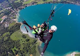 Een man geniet van de sensatie van zijn tandemparagliding aan het meer van Annecy - acrobatische vlucht met Takamaka Annecy.
