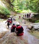 Freunde rutschen eine Naturrutsche hinunter während ihres Klassisches Canyoning im Canyon d'Angon, Talloires bei Annecy mit Takamaka Annecy.