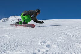 A snowboarder is slaloming during the Kids Snowboarding Lessons (6-13 y.) for Intermediates with the swiss ski school of Davos.