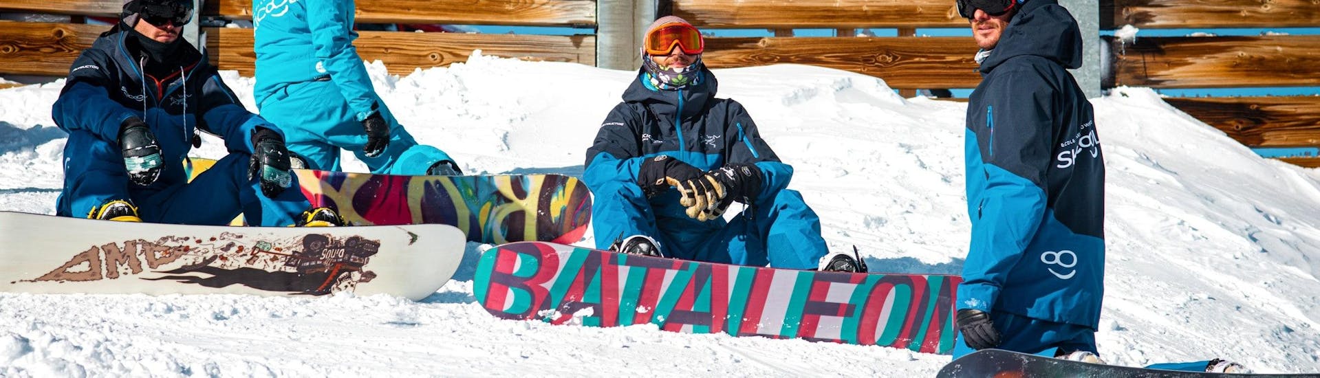 Gli snowboarder sono seduti sulla neve e aspettano l'inizio delle lezioni private di snowboard per tutti i livelli con Ski Cool Val Thorens.