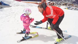 Il maestro di sci della Scuola di Sci Sertorelli Bormio sta insegnando al bambino a compiere i primi passi con gli sci sulla neve durante la lezione privata di sci per bambini di tutti i livelli .