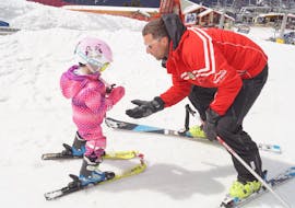 The ski instructor from Sertorelli Ski School Bormio is teaching a little kid the first steps on the snow during the Private Ski Lessons for Kids all Levels.