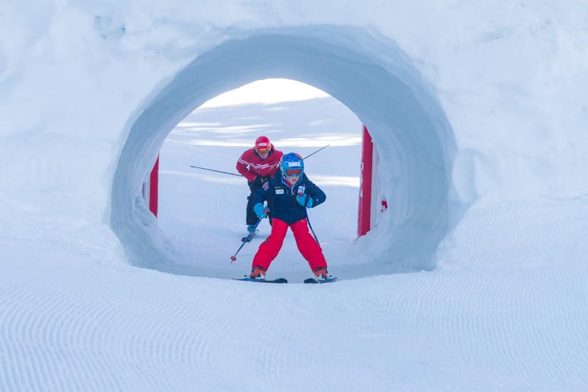 Der Skilehrer der Sertorelli Skischule Bormio verfolgt die Schritte des Kindes, das am privaten Skikurs für Kinder für alle Levels teilnimmt, genau.