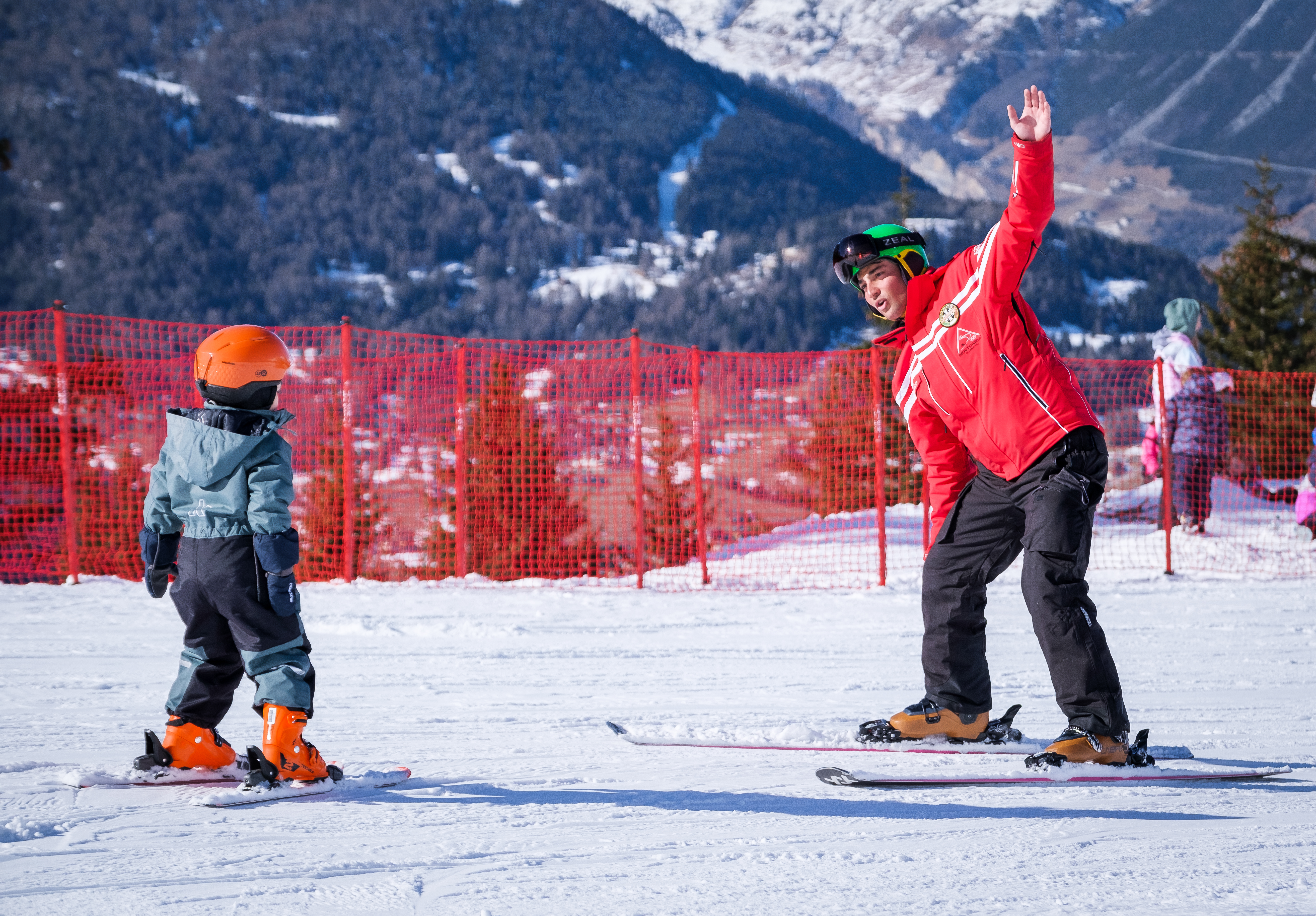 Der Skilehrer der Sertorelli Skischule Bormio verfolgt die Schritte des Kindes, das am privaten Skikurs für Kinder für alle Levels teilnimmt, genau.