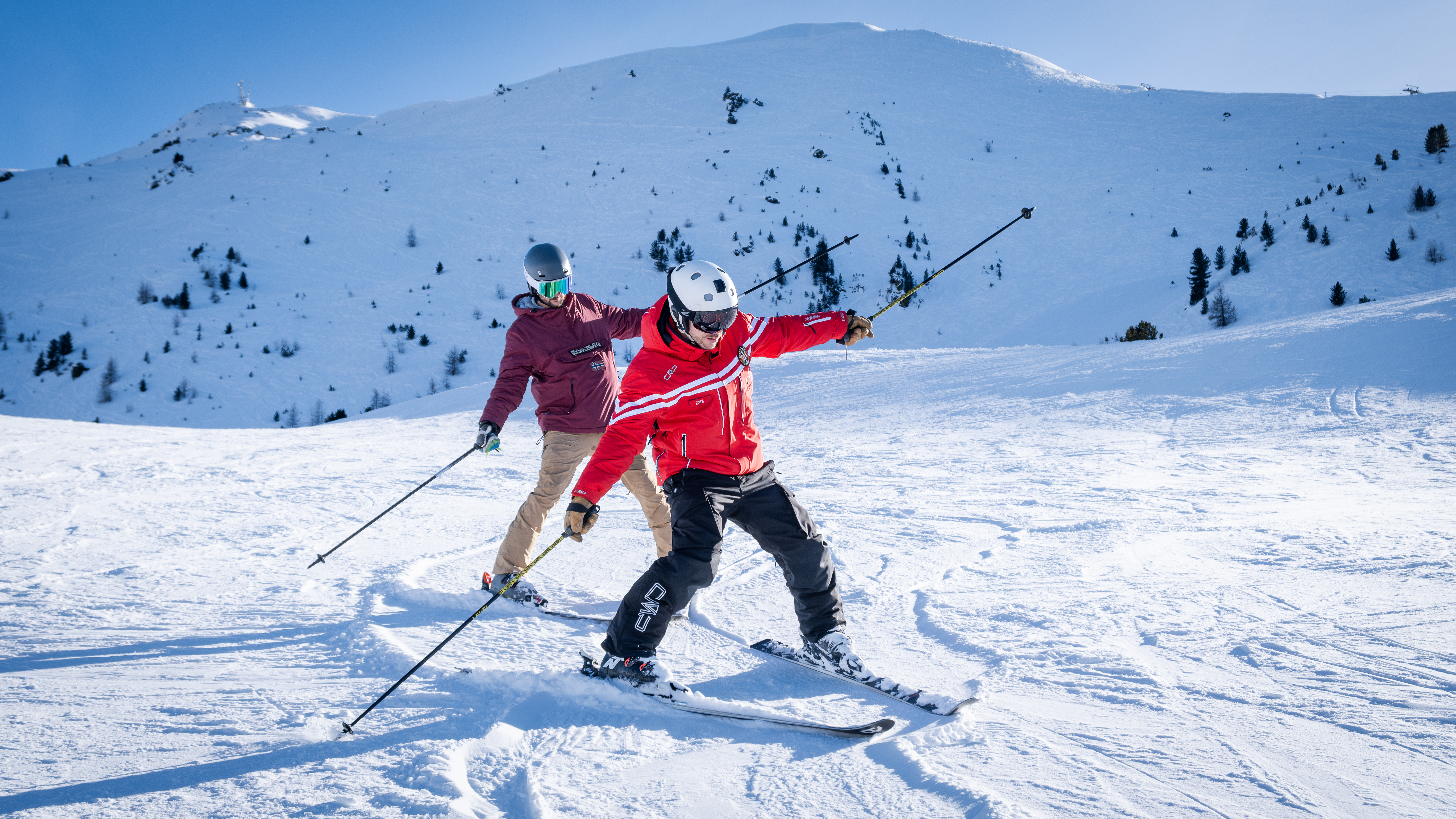 Der Skilehrer der Sertorelli Skischule Bormio fährt auf der Piste vor einem Teilnehmer des Privatskikurses für Erwachsene.