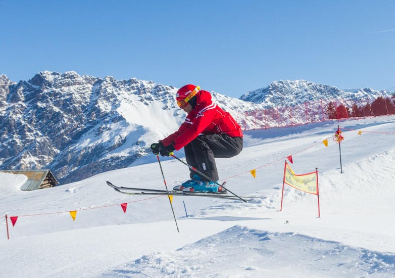 Der Skilehrer der Sertorelli Skischule Bormio springt in die Luft während einer der privaten Freestyle-Skikurse für alle Levels.