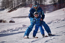 Enfants et moniteur de ski à Livigno pendant un des cours de ski pour enfants pour débutants.