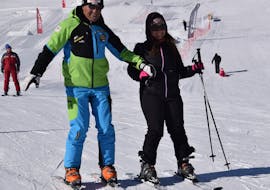 Participant et moniteur de ski profitant de la neige de Livigno pendant l'une des cours de ski pour adultes de tous niveaux.