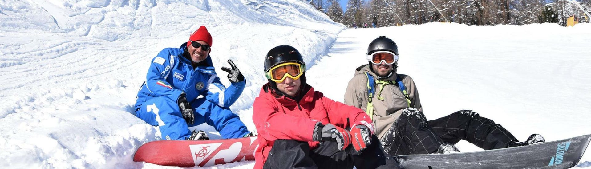 Due snowboarder e il loro istruttore si prendono una breve pausa dalle lezioni di snowboard per bambini e adulti - Bassa Stagione organizzate dalla Scuola di Sci e Snowboard Livigno Italia.