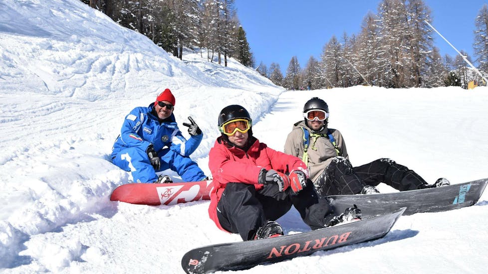 Twee snowboarders en hun instructeur nemen een korte pauze van hun Snowboardlessen voor Kinderen & Volwassenen - Alle Niveaus georganiseerd door de skischool Scuola di Sci e Snowboard Livigno Italy. 