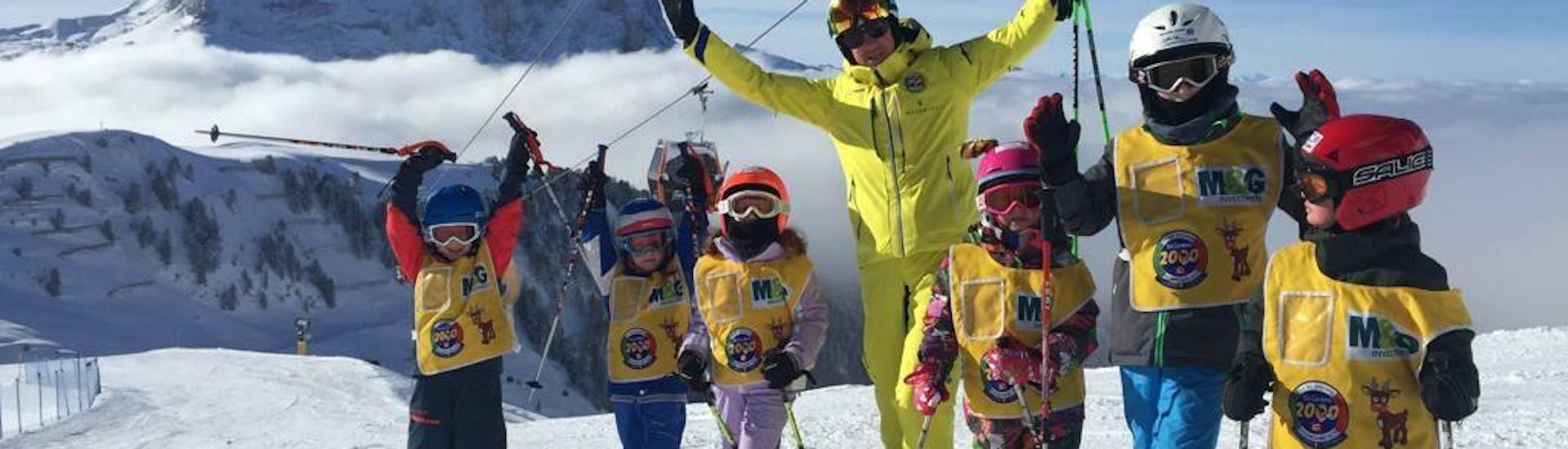 Maestro di sci e bambini a Selva di Val Gardena (Wolkenstein) durante una delle lezioni private di sci per bambini di tutti i livelli.