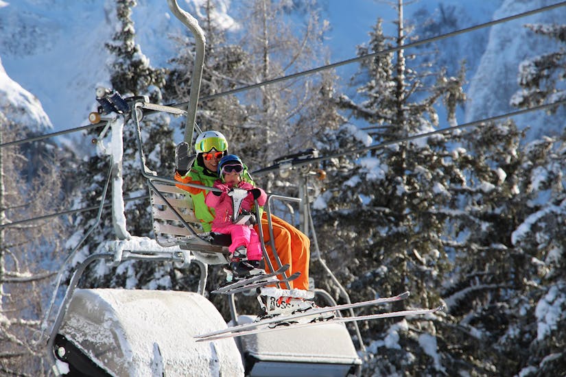 Skileraar en kind op de stoeltjeslift beginnen met een van de privé skilessen voor kinderen van alle niveaus in Folgarida.