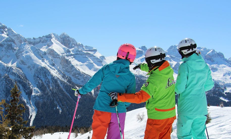 Maestro di sci che mostra le belle montagne di Folgarida durante una delle lezioni private di sci per adulti di tutti i livelli. 