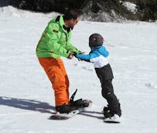 Formazione del maestro di sci e del partecipante per la prima volta durante una delle lezioni private di snowboard per bambini e adulti di tutti i livelli a Folgarida.