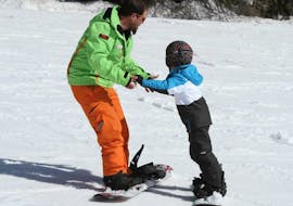 Moniteur de ski et participant s'entraînant pour la première fois pendant l'un des cours particuliers de snowboard pour enfants et adultes de tous niveaux à Folgarida.