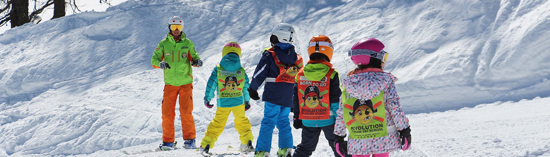 Moniteurs de ski et enfants sur les pistes de Folgarida pendant l'un des cours de ski pour enfants de tous niveaux d'une journée.