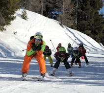 Maestro di sci e bambini in gara durante una delle lezioni di sci per bambini di tutti i livelli mezza giornata a Folgarida.