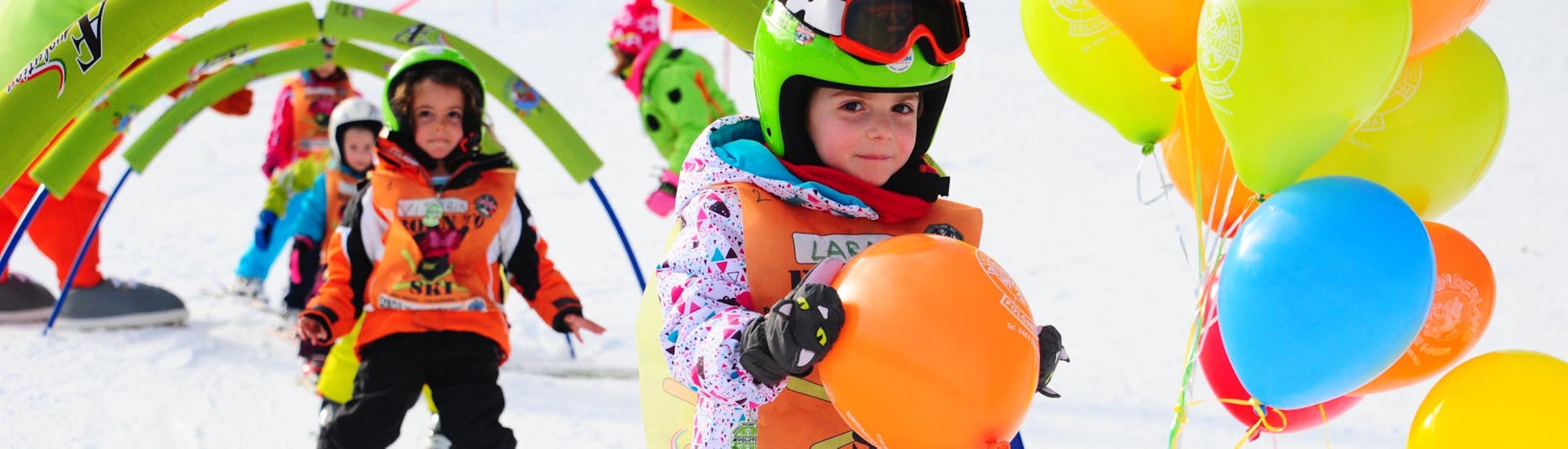 Les cours de ski pour enfants (4-13 ans) - tous niveaux de l'école de ski AEvolution Folgarida se déroulent dans l'espace de l'école ; un enfant a franchi les obstacles et a gagné un ballon.