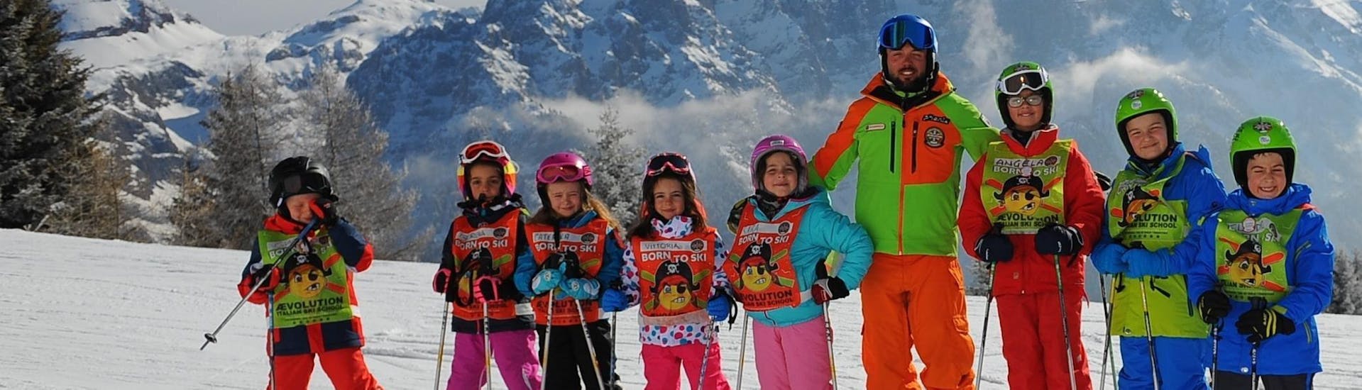 Le Lezioni di sci per bambini Mezza Giornata (4-13 a) - Natale della Scuola di Sci AEvolution Folgarida stanno per cominciare, bambini e maestro di sci posano per una foto. 