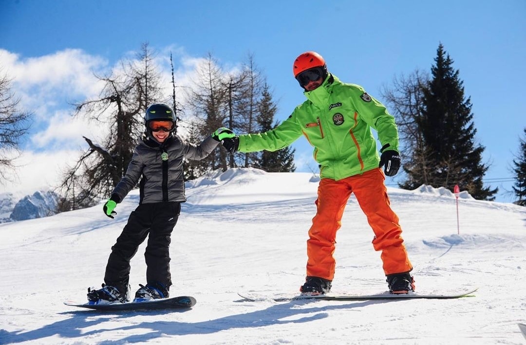 Pugno contro pugno sulle piste di Folgarida durante una delle lezioni di snowboard per bambini e adulti di tutti i livelli.
