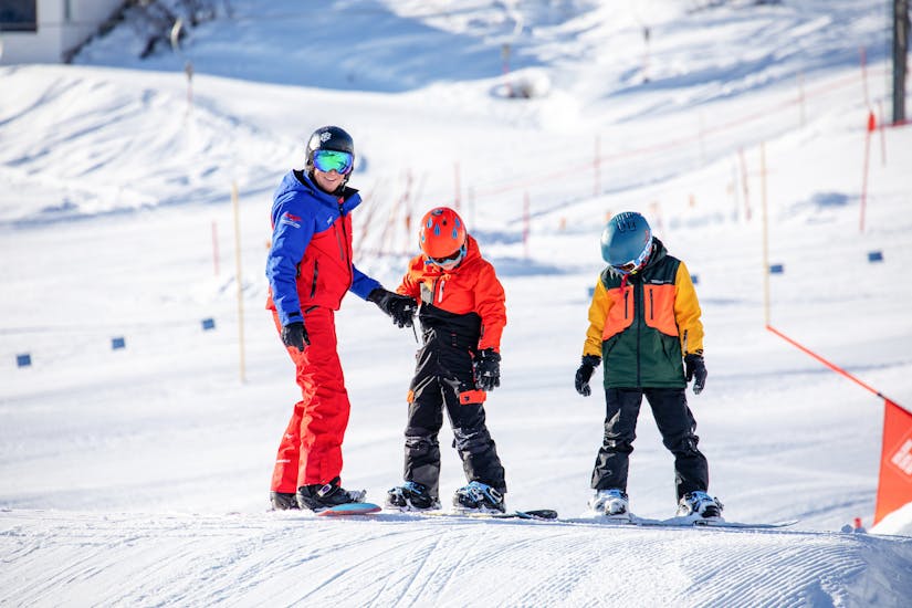 Snowboarder jumps on piste in snowboard course for children & adults - advanced.