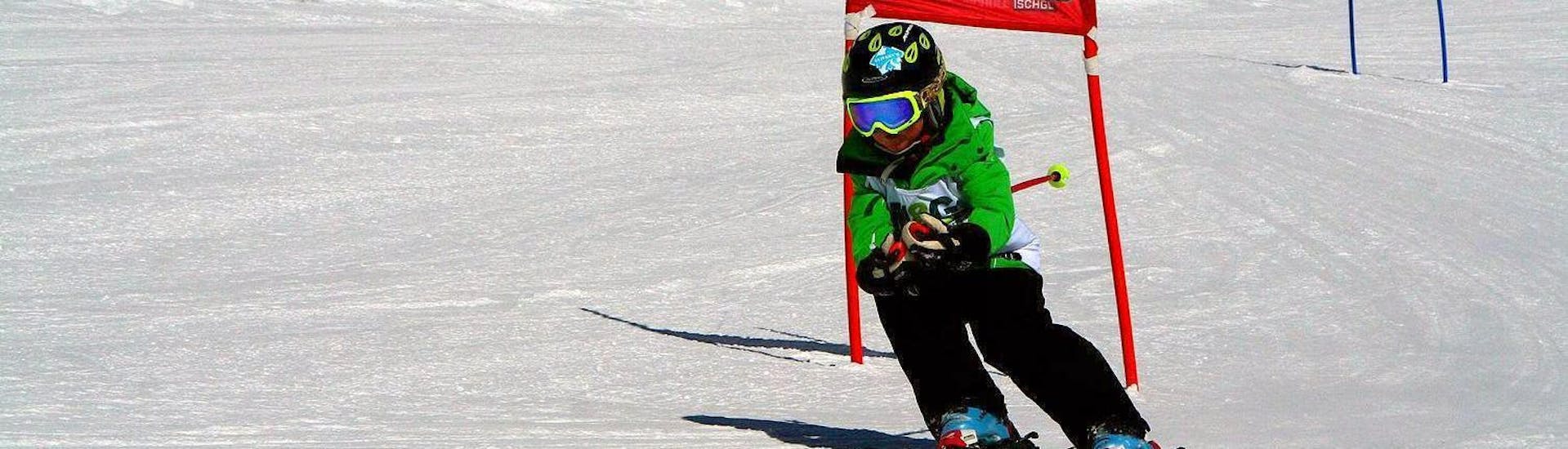 Un jeune enfant dévale une piste de course pendant l'un de ses cours de ski pour enfants (6-15 ans) - niveau expérimenté dans la station de ski d'Ischgl.