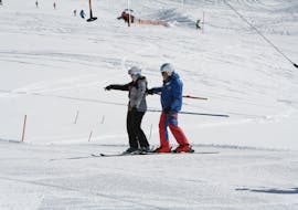 Un moniteur de ski aide un enfant à faire ses premières descentes dans le cours de ski pour adultes - Premier cours de l'école de ski Skischule Ischgl Schneesport Akademie.