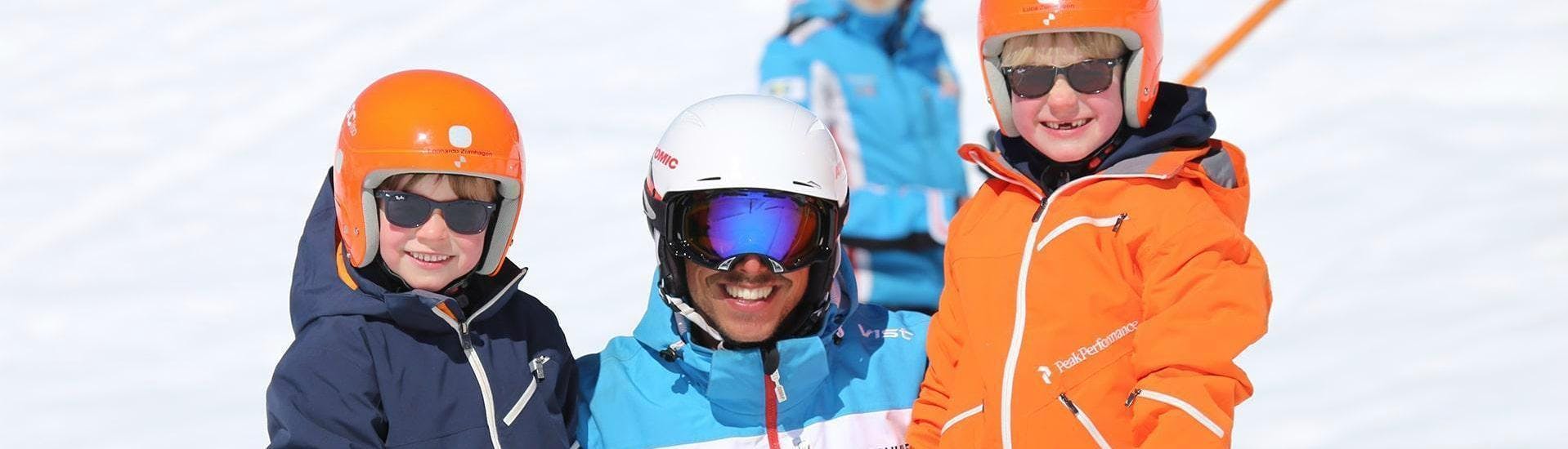 Zwei Kinder und ihr Skilehrer lächeln in die Kamera und genießen das Angebot Privater Kinder Skikurs - Alle Levels im Skigebiet Ischgl.
