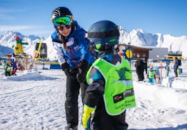 Una maestra di sci tiene per mano un bambino durante alcune lezioni private di sci per bambini - Tutti i livelli della scuola di sci Skischule Ischgl Schneesport Akademie.