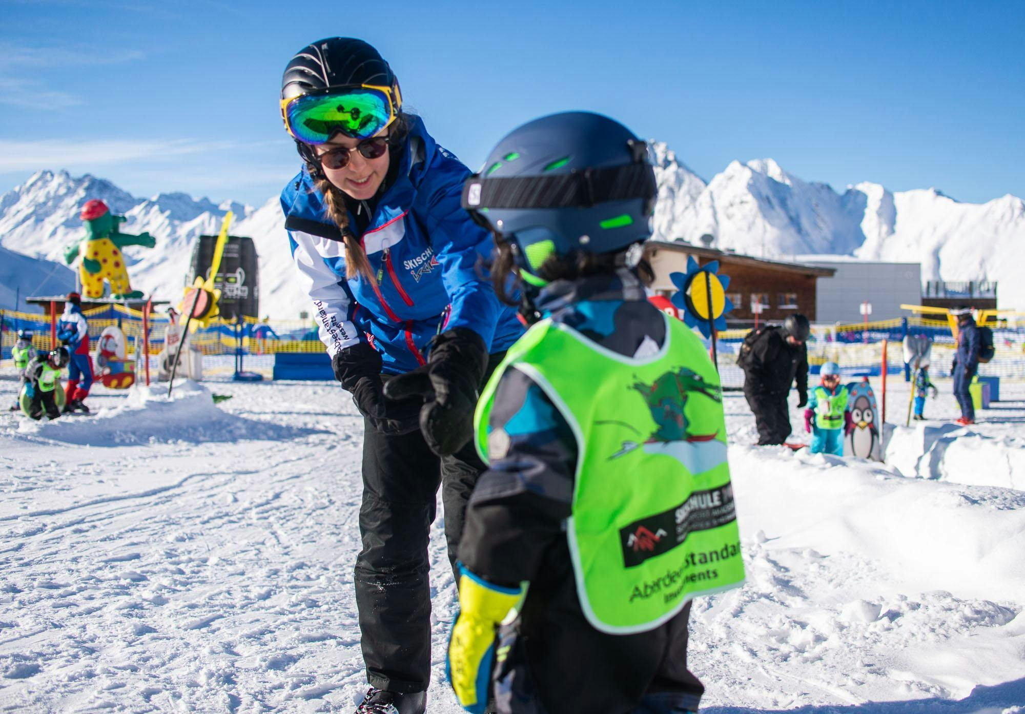 private-ski-lessons-for-kids-all-levels-skischule-ischgl-schneesport-akademie Ein Skilehrer hält im Privater Kinder Skikurs - Alle Levels der Skischule Ischgl Schneesport Akademie.