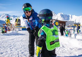 A ski instructor holds a child in her hand during some Private Ski Lessons for Kids - All Levels of the ski school Skischule Ischgl Schneesport Akademie.