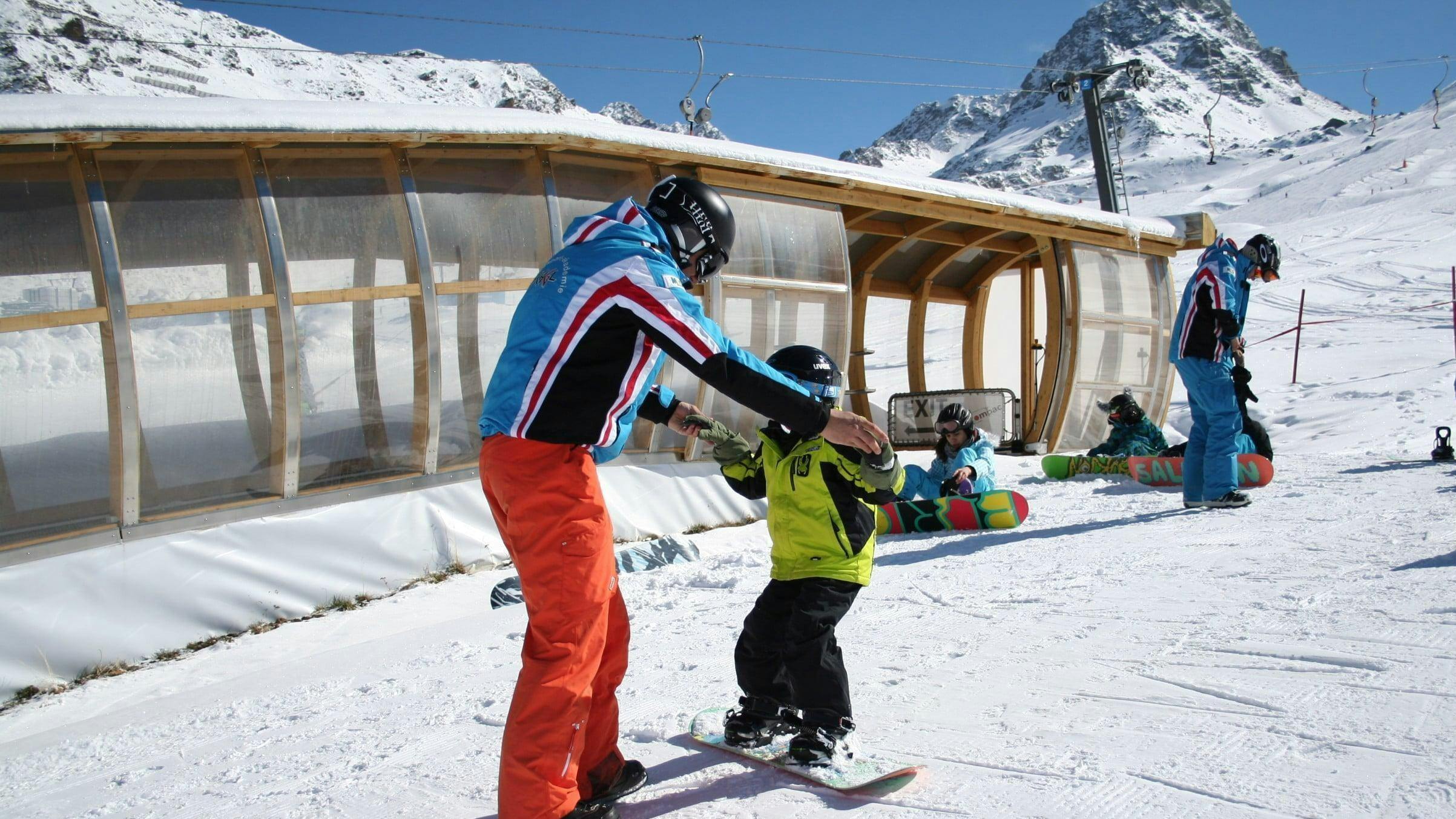 private-snowboarding-lessons-for-kids-adults-all-levels-skischule-ischgl-schneesport-akademie Eine Snowboardlehrerin zeigt eine Übung im Privater Snowboardkurs für Kinder & Erwachsene - Alle Levels der Skischule Ischgl Schneesport Akademie.