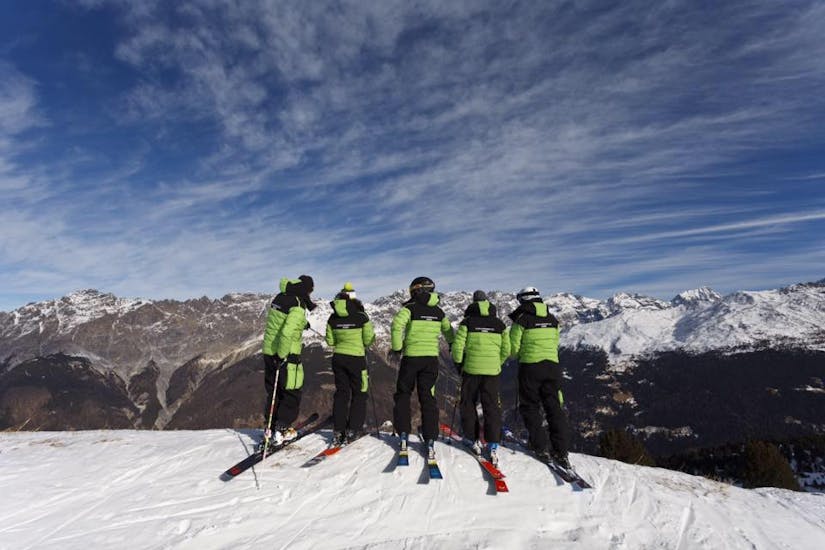 Des moniteurs de ski devant les montagnes à Bormio avant l'un des cours particuliers de ski pour Enfants de Tous Niveaux et de Tous Âges.