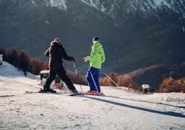 Two adults are enjoying the tailored-made Private Ski Lessons for Adults - All Levels under the guidance of an instructor from the ski school Scuola di Sci B.foxes.