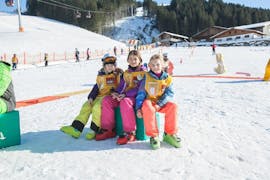 Drie kinderen ontspannen terwijl ze genieten van hun tijd tijdens de kinderskilessen "Snow & Fun 4 Kids" (4-6 j.) met Skischule Alpin-Profis Kirchberg/Tirol.