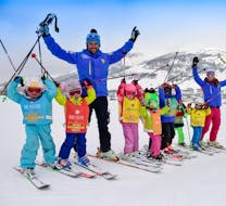 Eine Gruppe von jungen Skifahrern hat bei der von der Skischule Scuola di Sci Olimpionica in Sestriere angebotenen Aktivität Kinder Skikurs (5-12 J.) - Anfänger sichtlich Spaß mit ihrem Skilehrer.