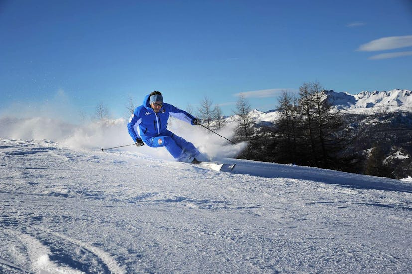 Ein Skilehrer der Skischule Scuola di Sci Olimpionica in Sestriere demonstriert im Rahmen des Angebots Skikurs für Erwachsene - Fortgeschritten die richtige Skitechnik.