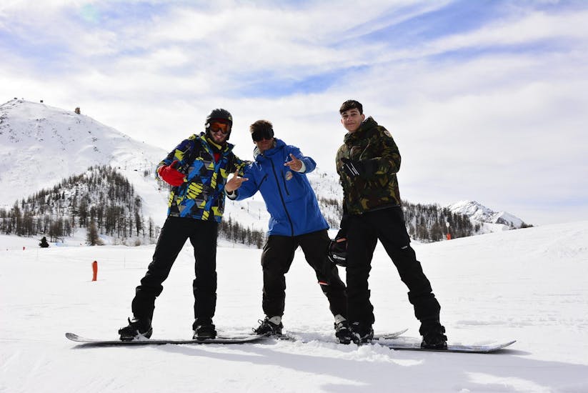 Een groep vrienden geniet van hun Snowboardlessen voor Kinderen & Volwassenen - Alle Niveaus georganiseerd door de skischool Scuola di Sci Olimpionica op de pistes van het Via Lattea skiresort in Sestriere.