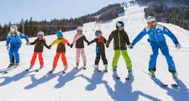 A group of children have fun in the snow during their kids ski lessons for first timers with the Schneesportschule Balderschwang.